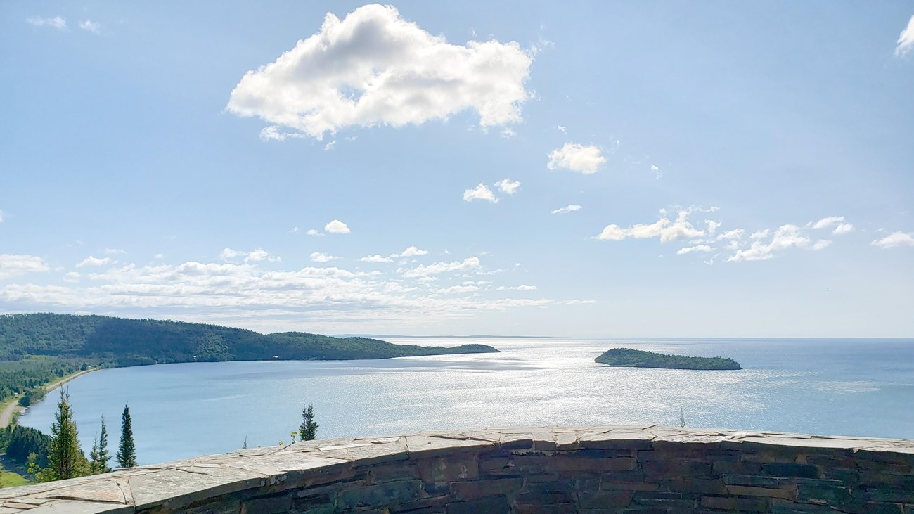 A stone wall in front of a lake view.