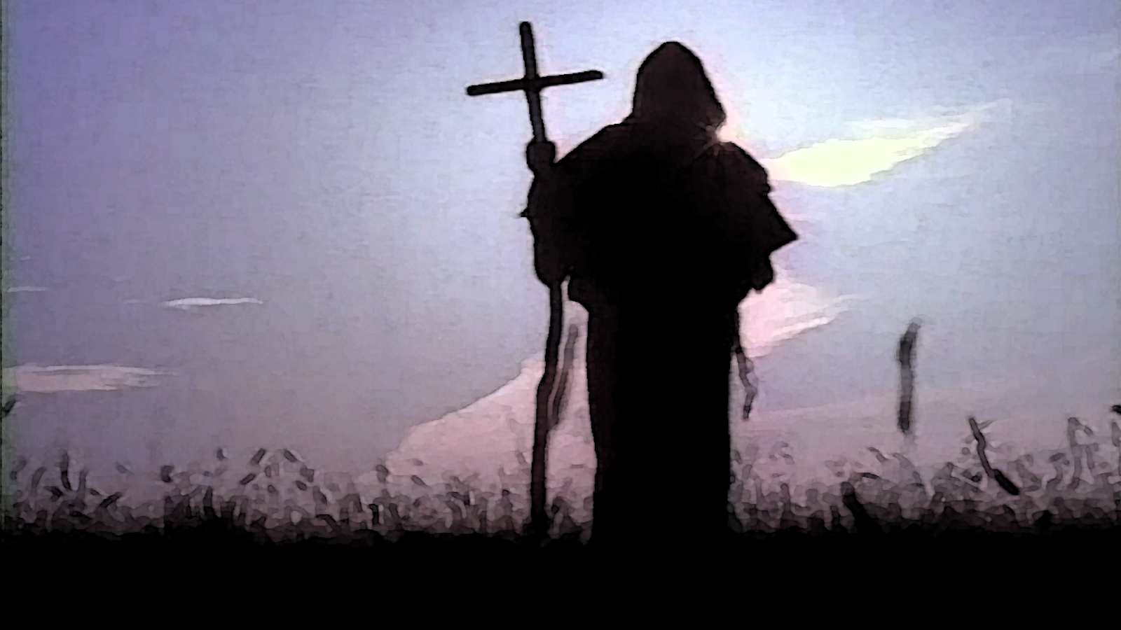 A robed priest prays before a wooden cross