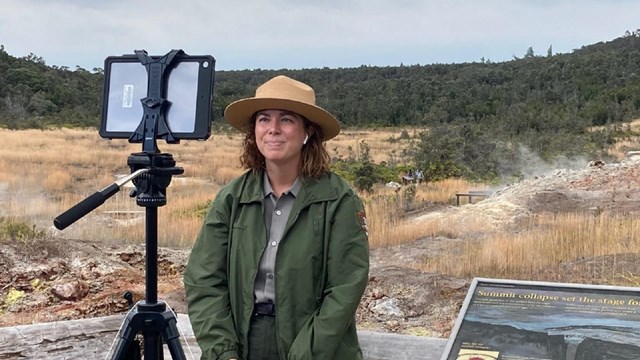 A ranger standing at an overlook providing a digital education program with an iPad.