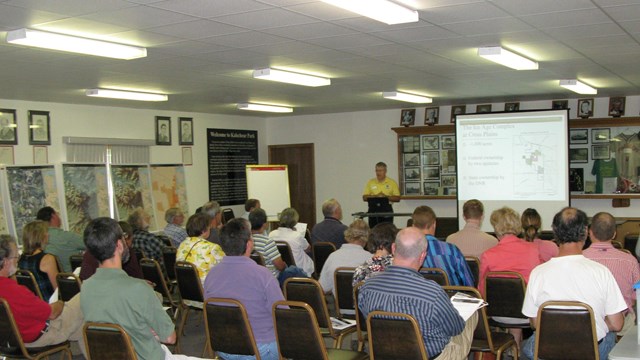 Participants listen to a presentation during an open house.