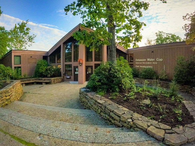 Park headquarters with its multiple large rectangle windows sits down two concrete steps, and between a pair of stone walls with flower beds on either side.