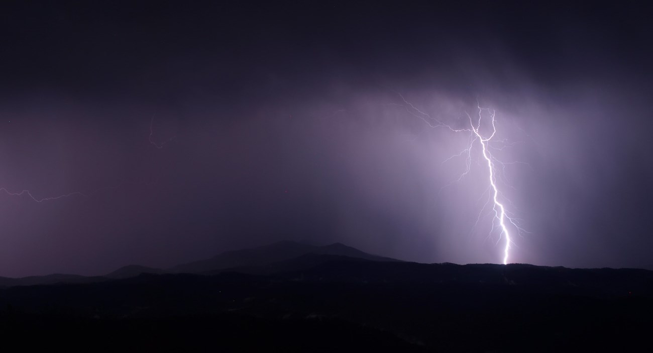 View from Look Rock Observation Tower. Lighting strikes, illuminating the mountains and sky of clouds in a purple hue.