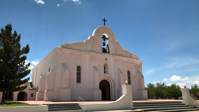 A spanish style mission in front of a blue sky.