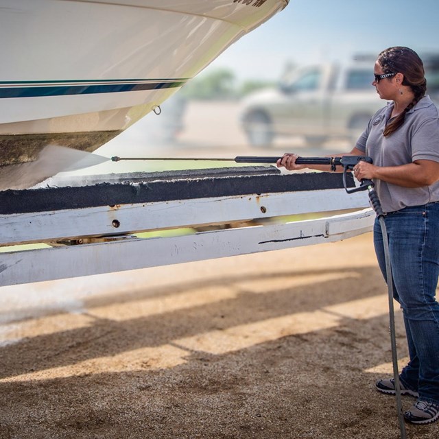 Woman power washing boat