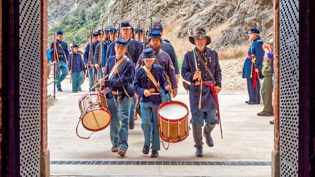 Civil War era reenactors with fife and drum march into Fort Point NHS