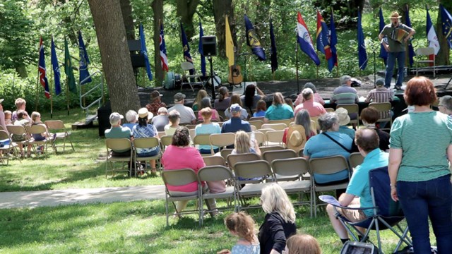 People sit facing a stage while a performer plays.