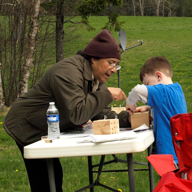 Woman shows boy how to do an activity