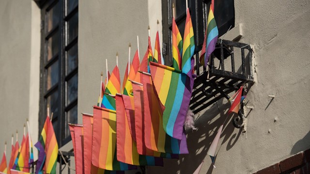 A rainbow flag overlaid with "Stonewall National Monument, Established 2016" with the NPS arrowhead.