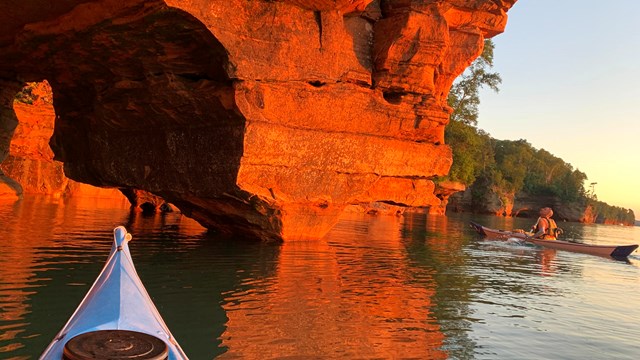 Kayaker looking up at a rock formation from the water. 