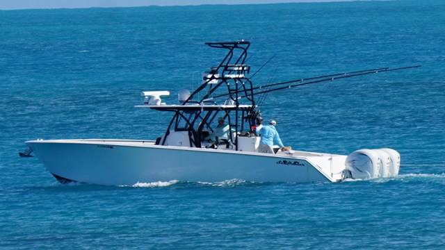 A boat floating on the ocean, passing 2 sandy islands