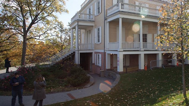 A yellow house is surrounded by fall foliage.