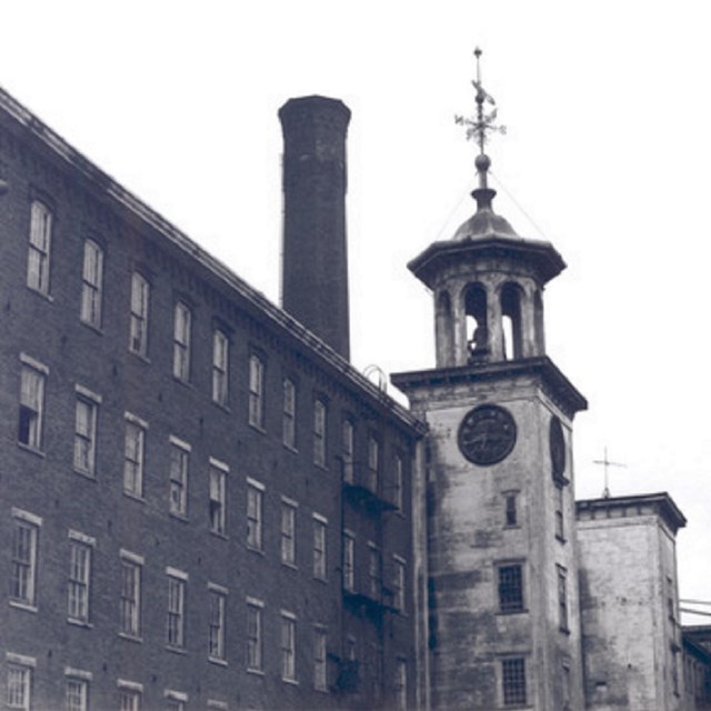 A mill tower and chimney, with the paint on the tower weathered.