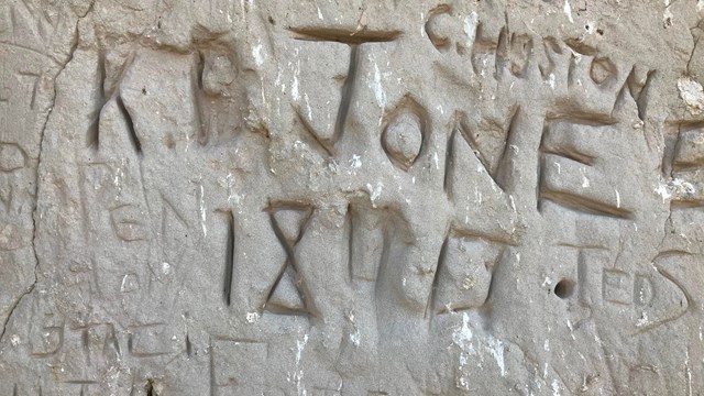 Old names scratched into a rock face.