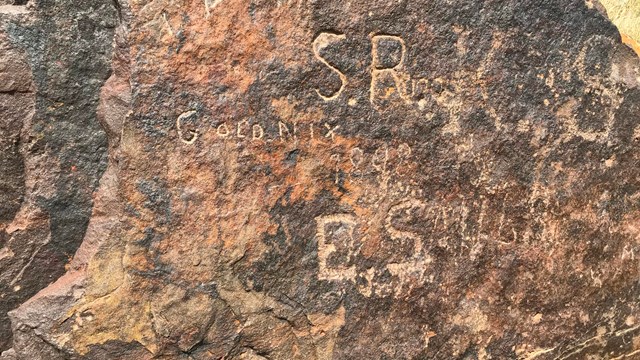 Written inscriptions scratched into a large rock.