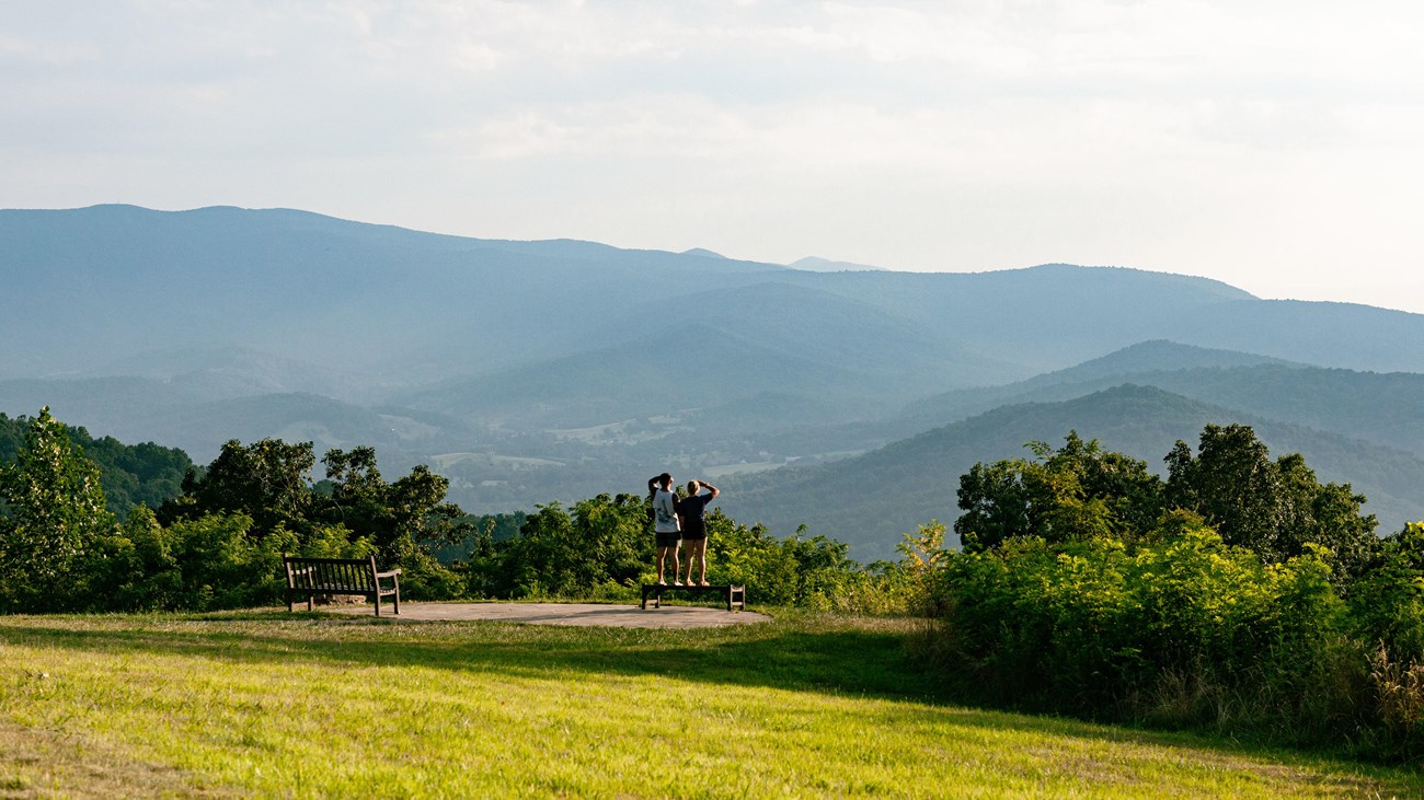 A couple standing on a bench at Dickey Ridge lawn, taking in the valley views.