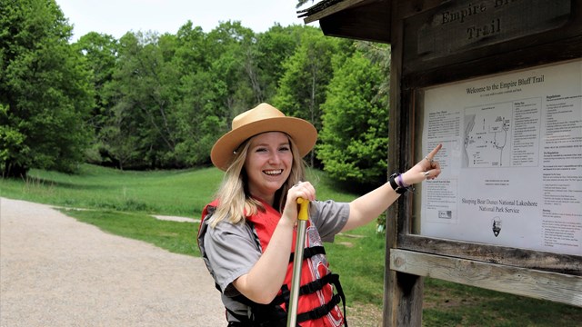 A ranger wearing a life jacket points to a map