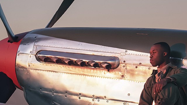 Tuskegee Airmen standing outside of P51 Mustang red tail. 