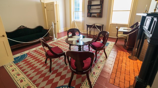 A wide angle view of the M'Clintock parlor, furnished with period furniture.