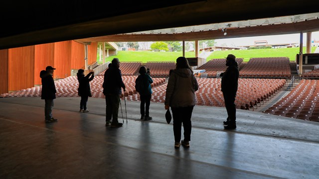 Ranger and visitors looking out into the Filene Center from the stage.