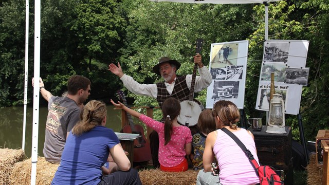 Musician performing under tent with audience at Canal Days.