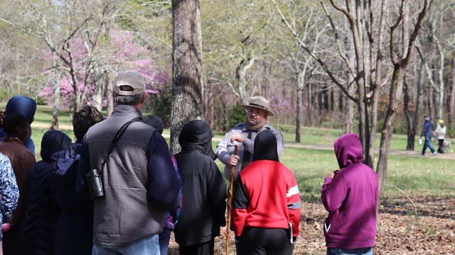 Several visitors in winter coats listen to park ranger 