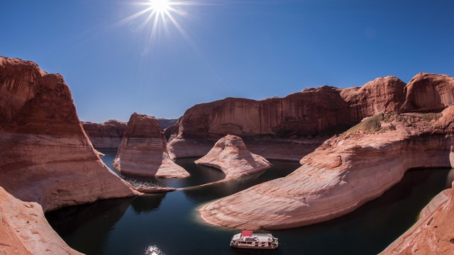 A houseboat winds through high cliffs.