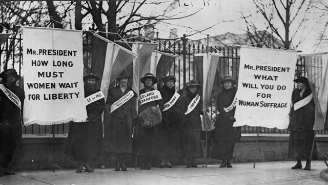 Suffragettes picket outside the White House fence.