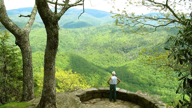 A woman stands on a flagstone patio overlooking a view of the mountains