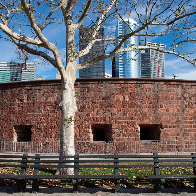 a round brick fort with tree in front and sidewalk