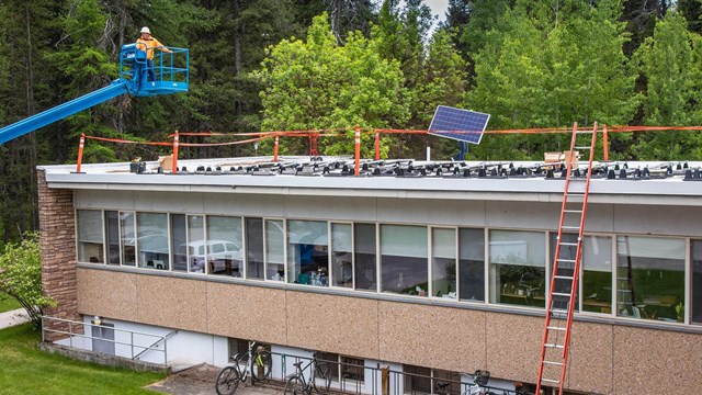 Lift carrying workers installing solar panels on top of a headquarters building's roof