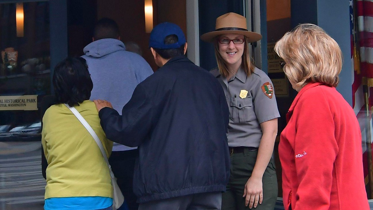 A ranger holds a door open for people