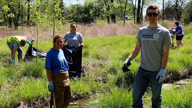 Volunteers clean up trash from a stream near Fortress Rosecrans.