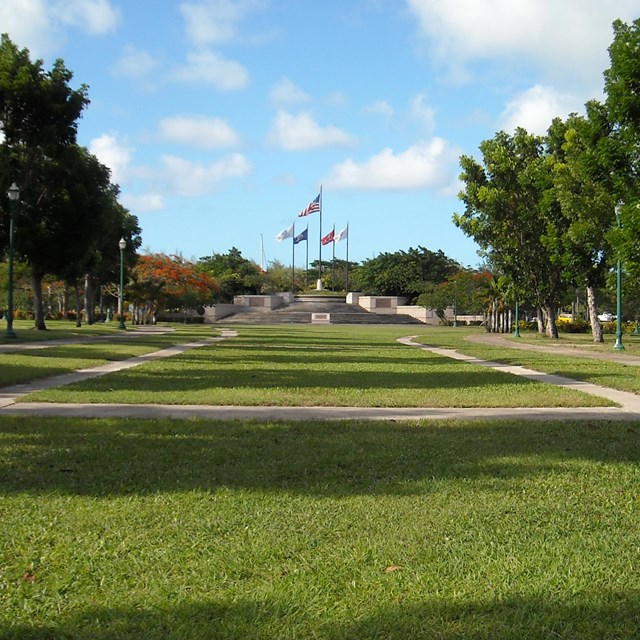 grassy field with white memorial in the distance. american flag in center