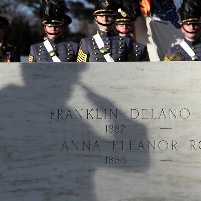 a shadow of a saluting soldier reflected on the marble grave of FDR