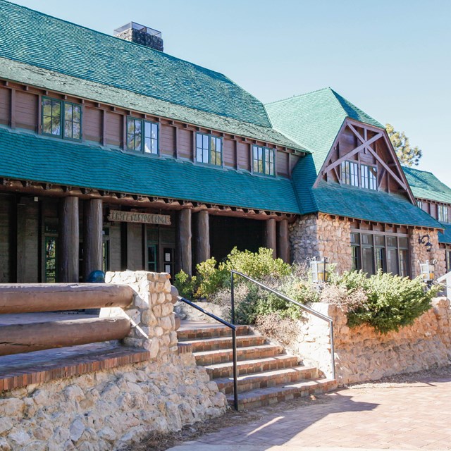 The exterior of a wooden building with a green shingled roof.