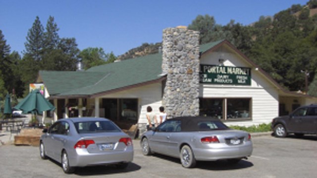 Exterior of a small white building with cars parked outside.