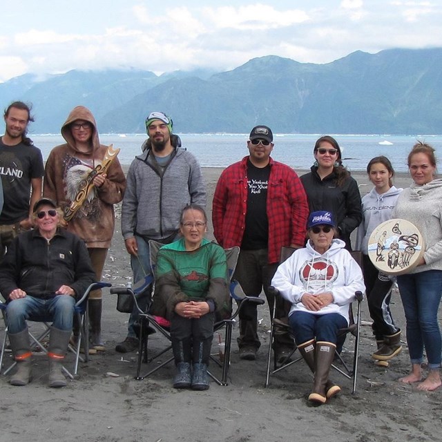 A group of people gathered on the beach. The group is made up of elders and youths.