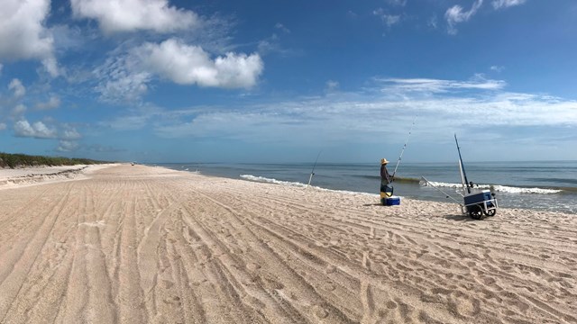 One fisherman fishing on the beach.