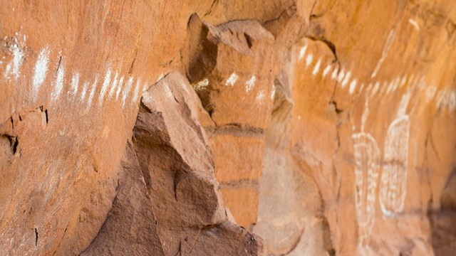 a row of white dots and shapes painted on a rock wall