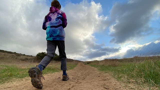 Kid walking on a dirt trail in a desert area