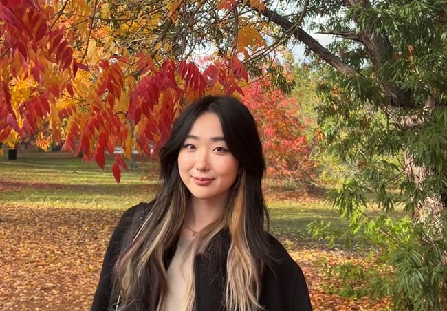 A woman smiling with leaves in the background