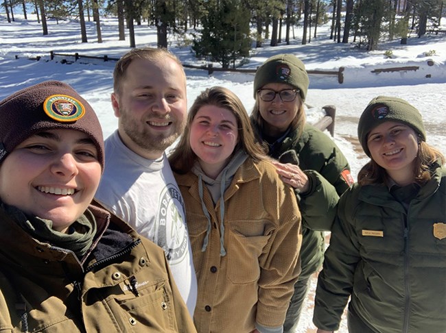 A man and a woman surrounded by park rangers in uniform