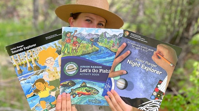 Several kids hold up junior ranger program materials