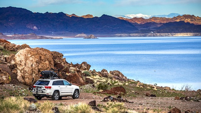 View of a lake with camping vehicle in front of it.