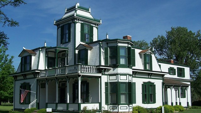 White sided house with forest green shutters and trim