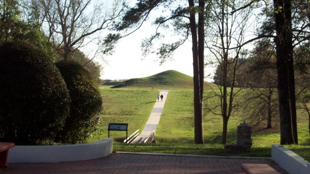 People walk up the path to the earth lodge.