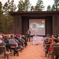 A ranger stands in front of a screen before a seated audience.