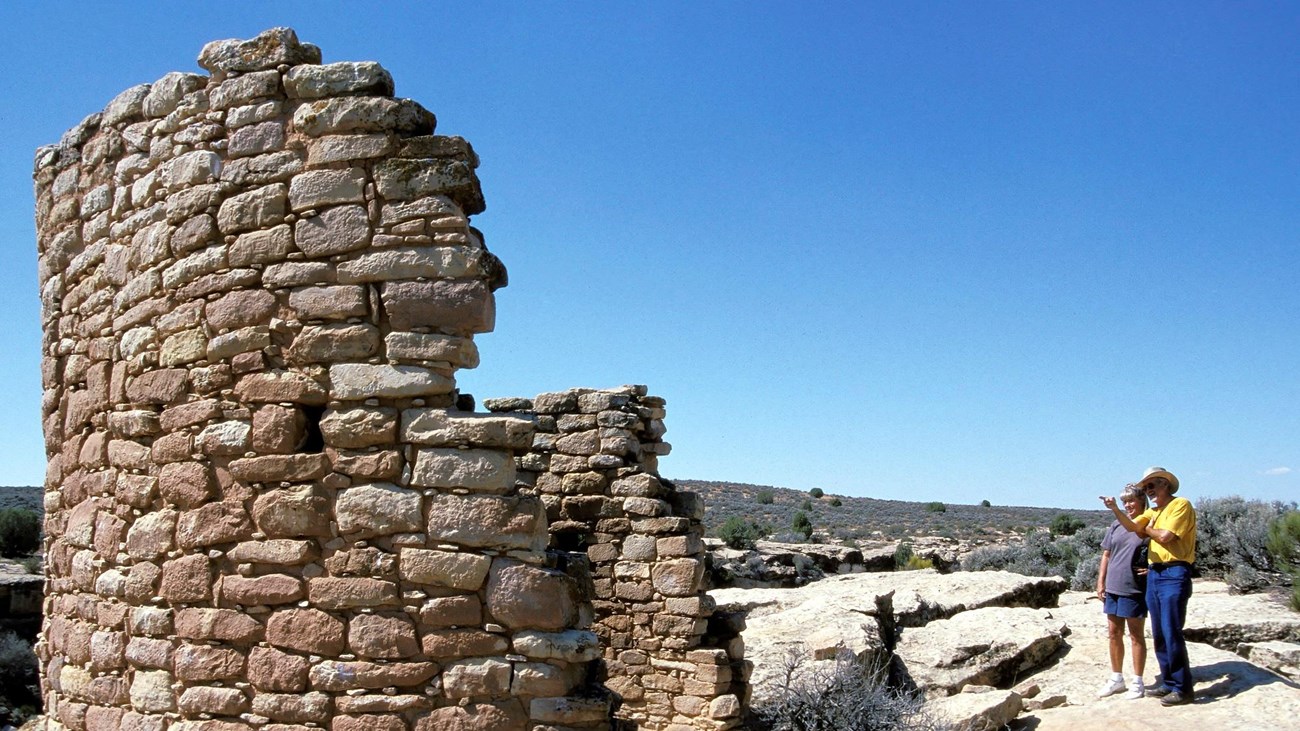 two people look at a partially collapsed round tower made of stones