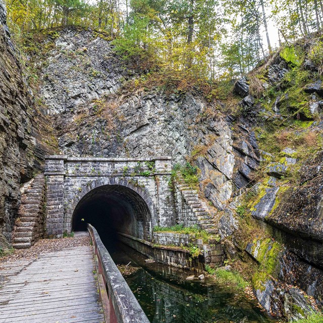 Jagged rock walls surround the arched Paw Paw Tunnel enterance.