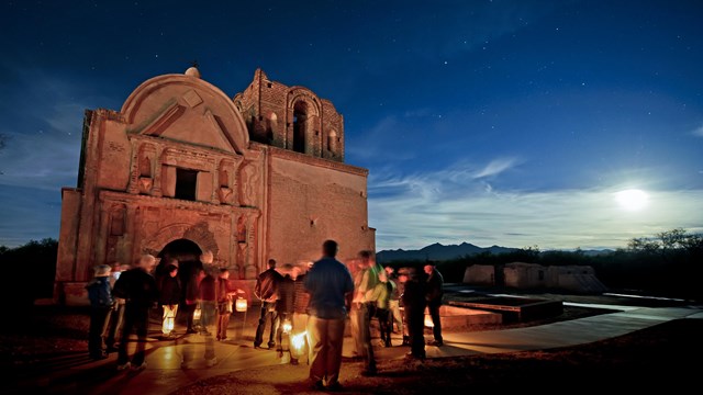 Group of people at dusk standing in front of building ruin